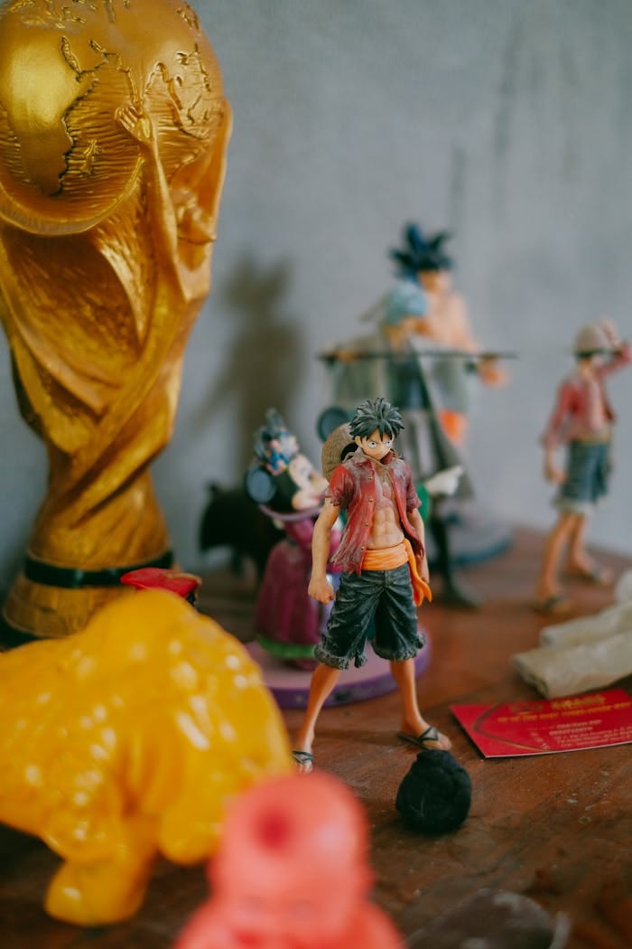 Colorful anime figures and a World Cup trophy on a wooden shelf.